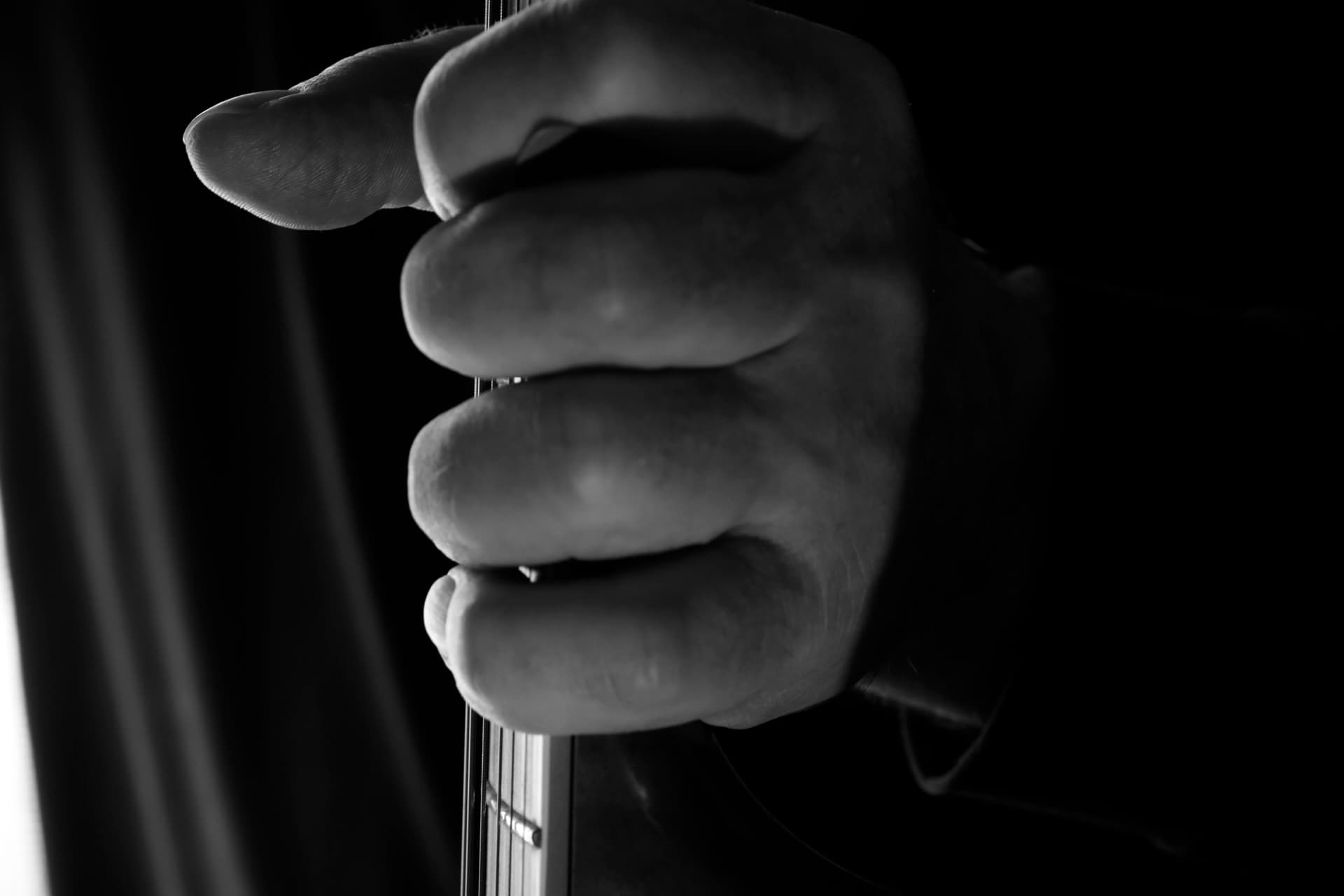 Hand gripping guitar neck in dramatic light